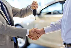 A dealer hands over the keys to a new car