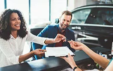 A couple signs paperwork to buy a car