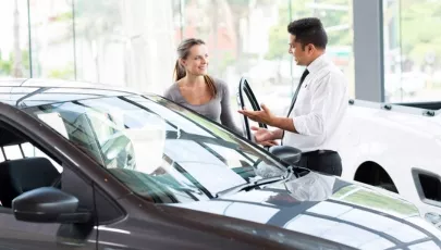 A car salesman shows a lady a car