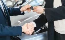 A dealership handing the keys to a customer for a new car