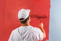 A painter painting a wall red