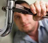 A plumber works on a sink