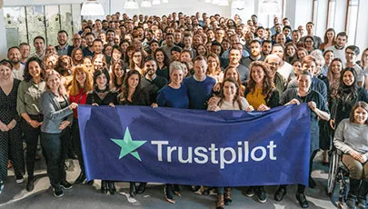 The Trustpilot team in front of a logo banner